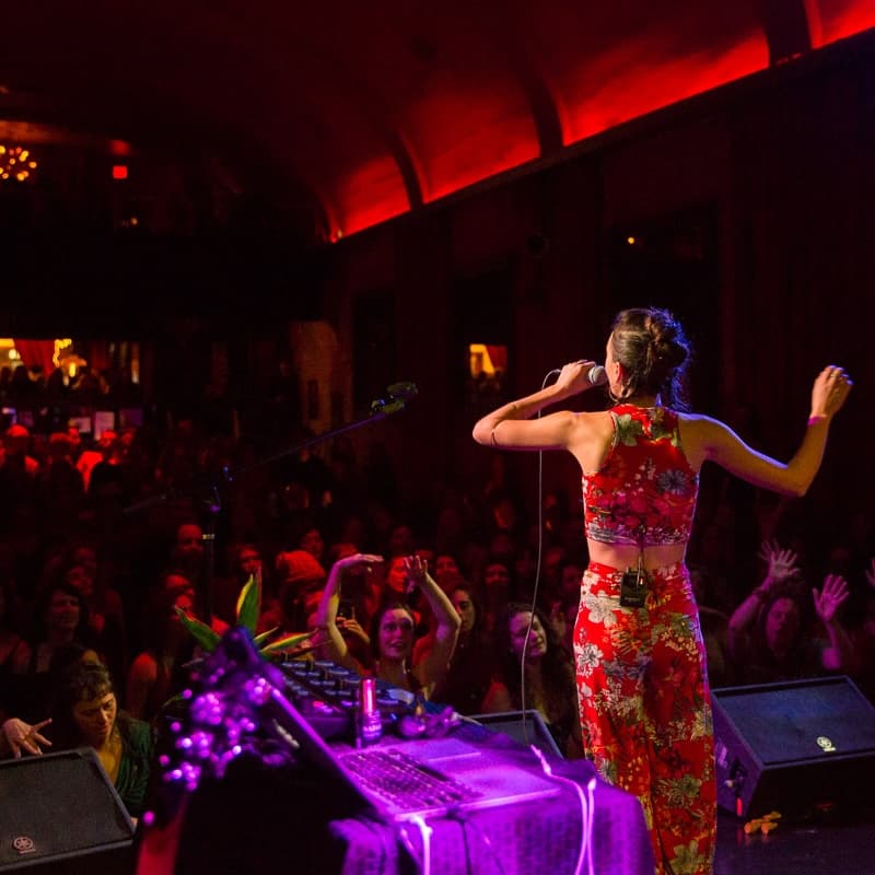 Ayla Nereo singing on stage under purple lights